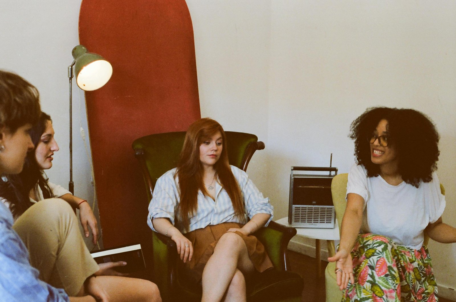 Four adults engaged in a relaxed group discussion in a cozy indoor space.